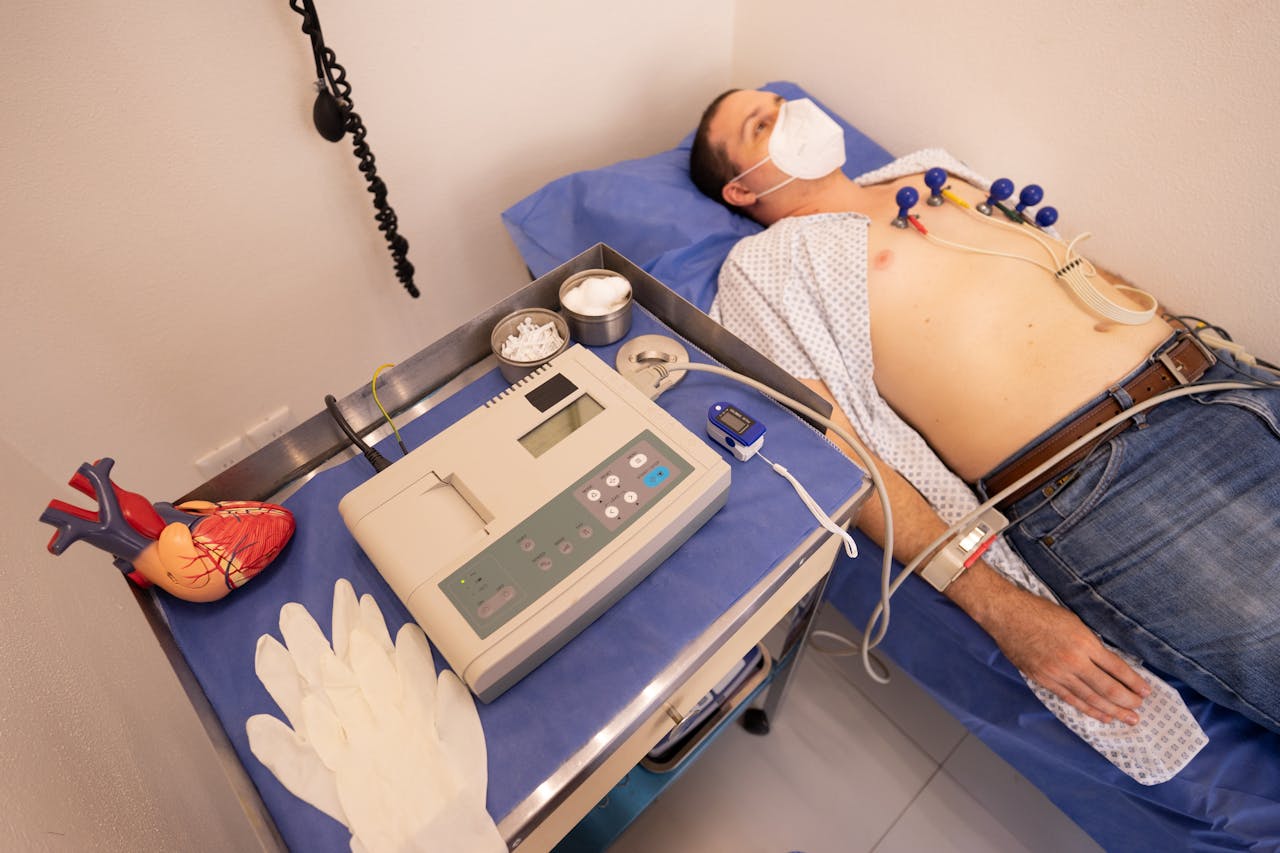 CardioClínico A man undergoing a cardiology exam with an ECG machine in a medical clinic.
